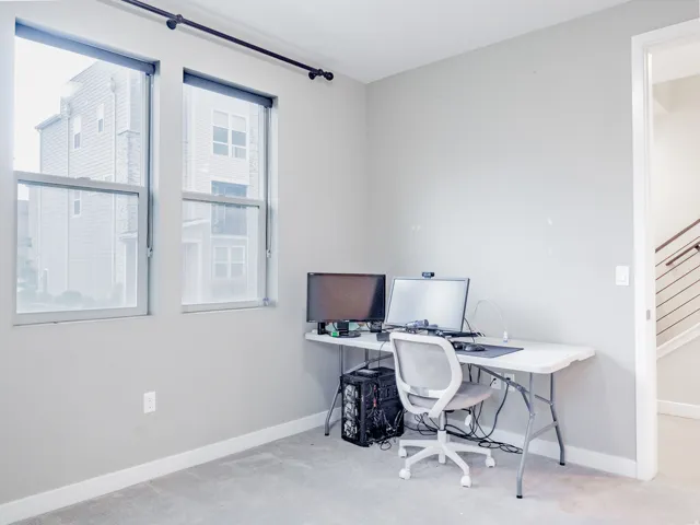 Room featuring light gray wall paint, two large windows, and gray carpet flooring