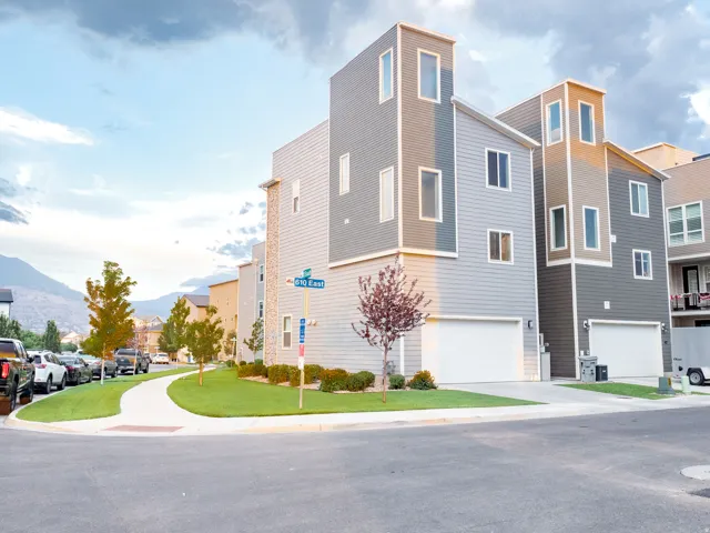Contemporary multi-level townhome featuring a mixed material facade, an integrated garage, and a manicured lawn