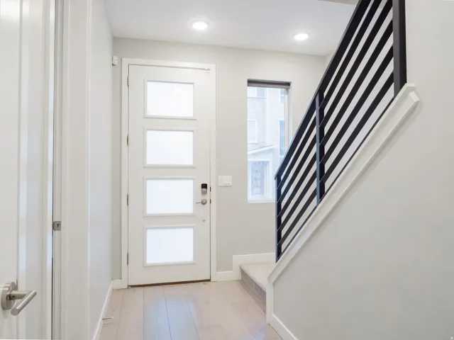 Entryway featuring a modern door with frosted glass panels, wood-finish flooring, and a contemporary staircase with black horizontal railings
