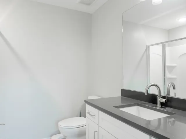 Bathroom vanity featuring a dark countertop, undermount sink, and brushed chrome faucet