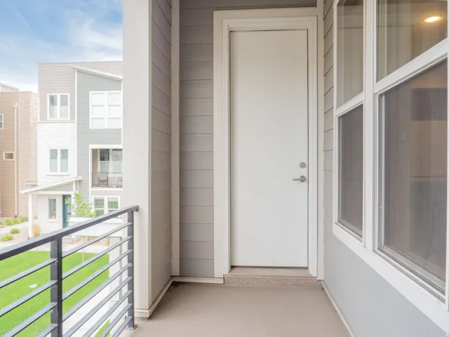 Private balcony featuring horizontal metal railings, a solid white exterior door, and a multi-pane window