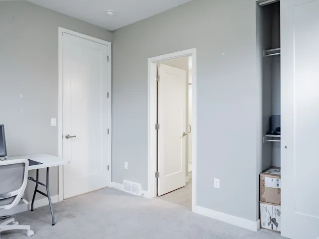 Light gray wall paint with white trim, a solid panel interior door, and light-colored carpet flooring