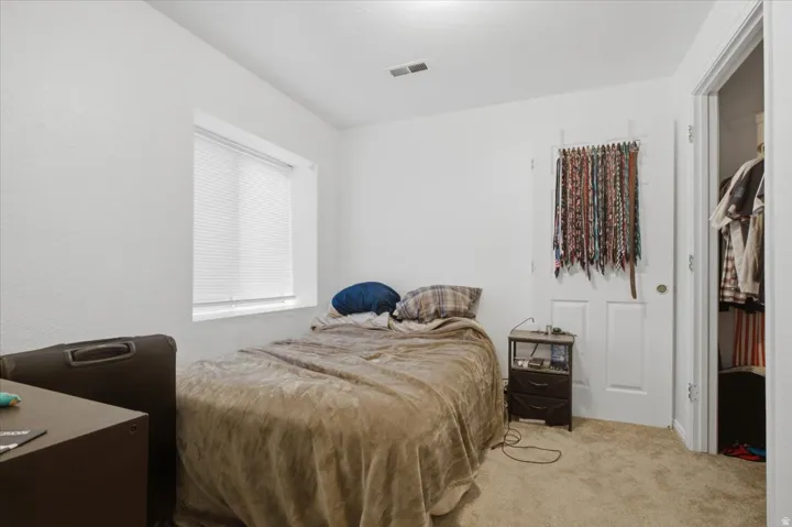 Carpeted room featuring white walls, a single window with blinds, and a white door leading to a closet