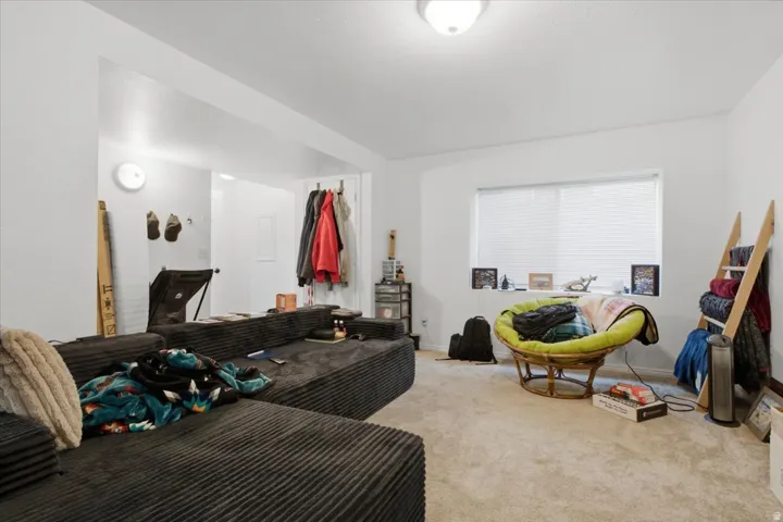 Spacious living area featuring light-colored carpeting and bright white walls