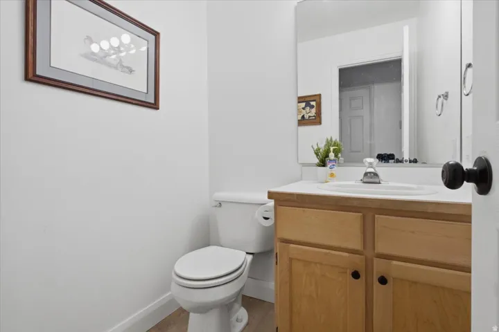 White wall vanity with a built-in sink, light wood-finish cabinetry, and a full-width wall mirror