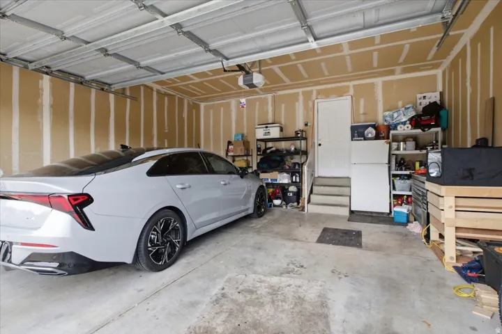 Spacious garage featuring a concrete floor, exposed wall studs, and overhead door
