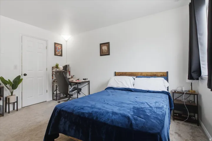 Carpeted bedroom with a window featuring dark privacy drapes