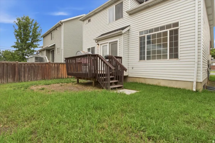 Rear exterior featuring a wooden deck with railing and stairs, vinyl siding, a multi-pane window, and a sliding glass door