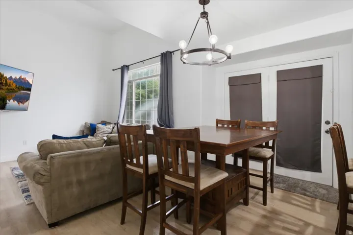 Open-concept living area featuring vaulted ceilings, wood-finish flooring, a contemporary chandelier, and French doors