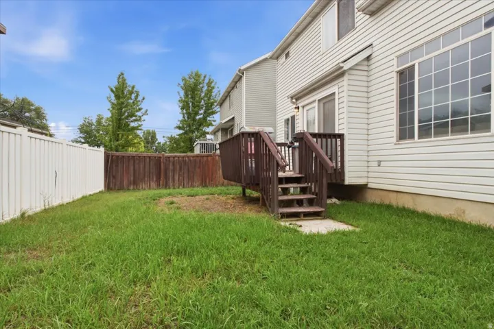 Private backyard space featuring a wood fence, a white vinyl fence, and a wooden deck with stairs