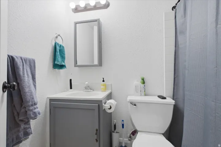 Bathroom featuring a gray vanity with an integrated sink, coordinating wall-mounted medicine cabinet, and a five-bulb vanity light fixture