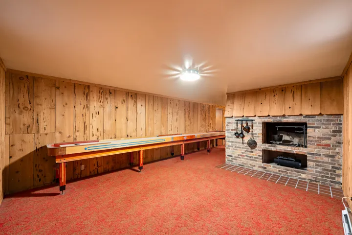 Recessed entertainment space featuring wood paneling, a brick fireplace, and red carpeting