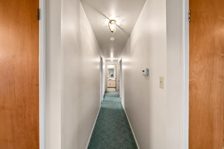Hallway featuring light-colored walls and green carpeting