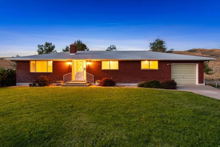 Brick ranch-style residence featuring a single-car garage with a roll-up door, a concrete driveway, and a front porch with white railings