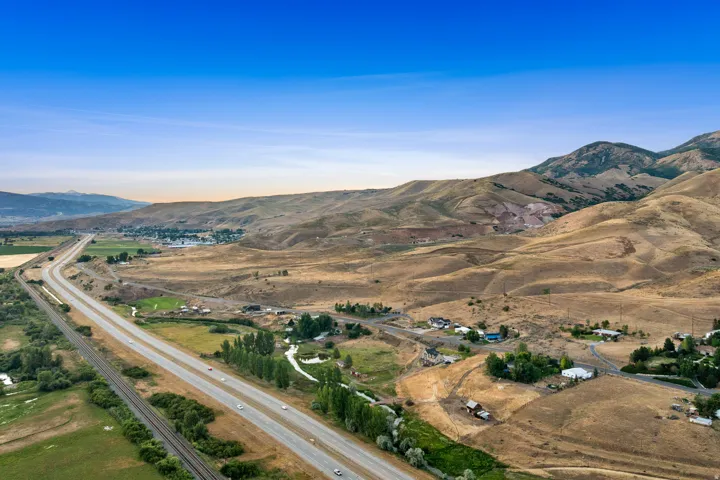 Expansive rural landscape featuring a highway, railroad tracks, and natural terrain with distant mountainous formations