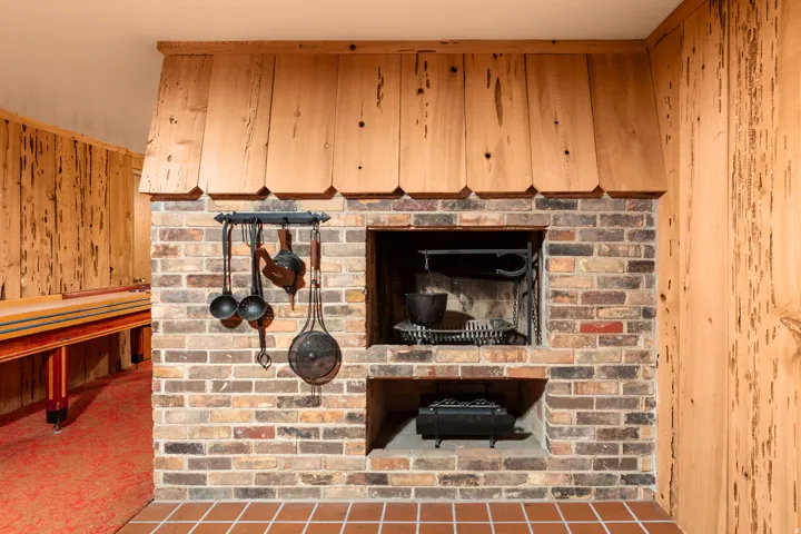 Brick fireplace with a wood-paneled hood, featuring an integrated hearth and brick flooring
