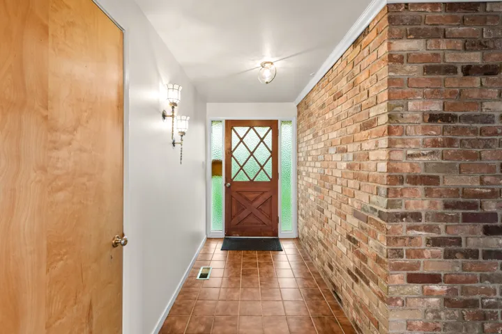 Entryway featuring a rich wood-finish door with diamond-patterned lites, complemented by frosted side panels