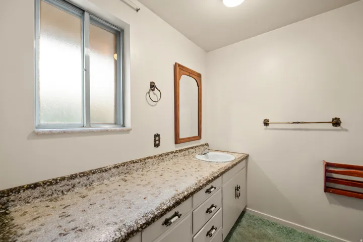 Bathroom featuring a built-in vanity with a speckled countertop, integrated sink, and white cabinetry