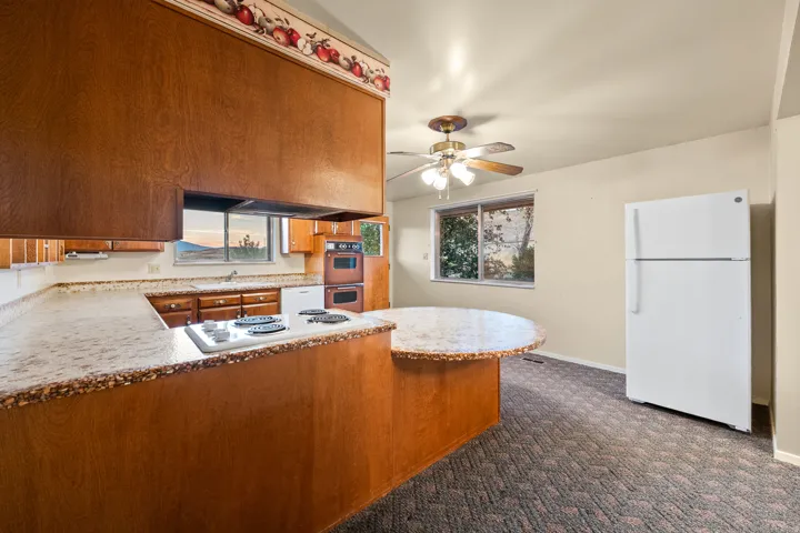 Kitchen featuring wood cabinetry, integrated cooktop, dual wall ovens, and a built-in circular dining area