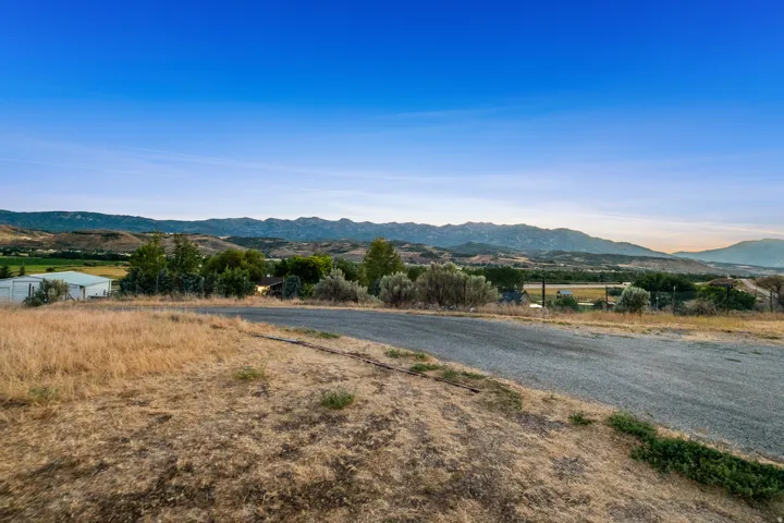 Expansive property featuring a gravel road, natural landscaping, and distant mountain ranges