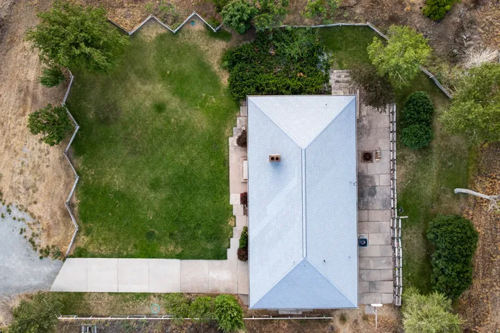 Gable roof residence with a central chimney, featuring an extensive concrete patio and a rectangular grassy area