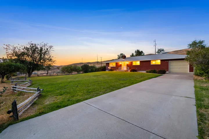 Brick facade residence with an attached garage, concrete driveway, and expansive front lawn