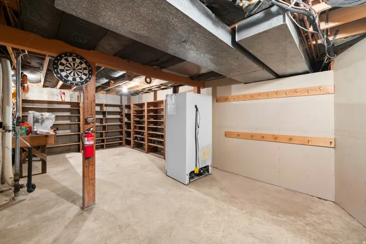 Unfinished basement space featuring exposed wood beams and concrete flooring
