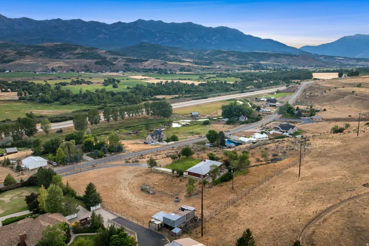 Expansive rural landscape featuring distant mountains, verdant fields, and scattered residential properties