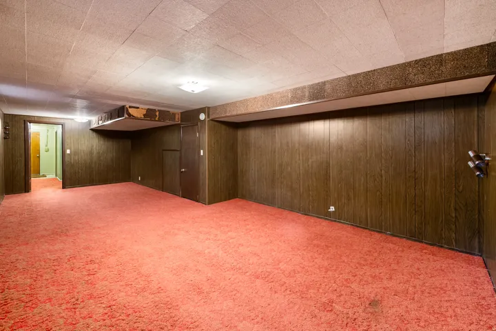 Spacious room with wood paneling, drop ceiling, and red carpeting