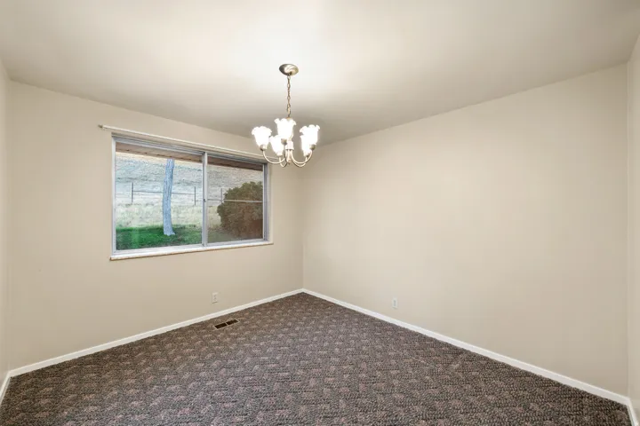 Interior room featuring a patterned carpet, neutral wall paint, and a window offering natural light