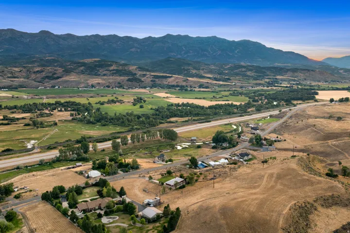 Expansive mountain backdrop with open fields and a winding highway