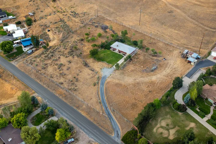 Sprawling property featuring a single-story residence, a long paved driveway, and extensive undeveloped land with natural vegetation