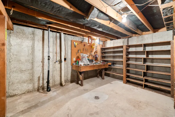 Unfinished basement space featuring exposed wood joists and concrete walls