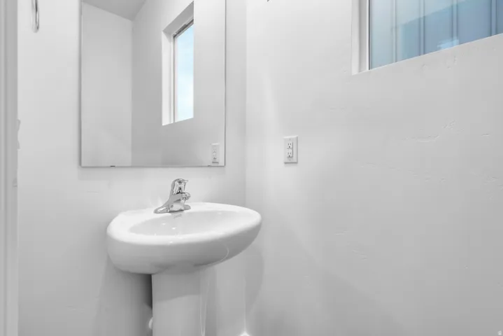 Pedestal sink with chrome faucet, complemented by a rectangular wall-mounted mirror