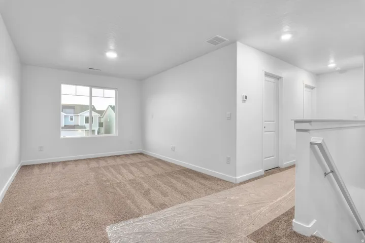 Carpeted room featuring a large multi-pane window, recessed lighting, and white baseboards