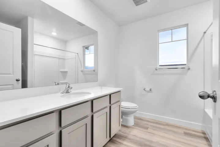 Bathroom featuring a single vanity with a white countertop, chrome faucet, and integrated sink