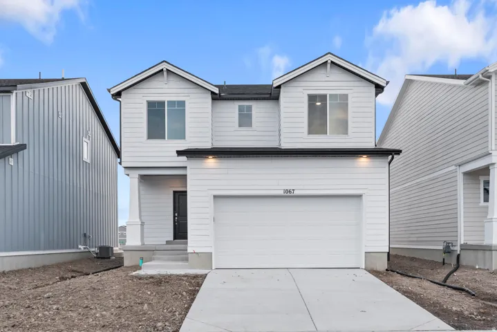 Modern two-story residence featuring light-colored siding, a two-car garage, and a covered entry with columns