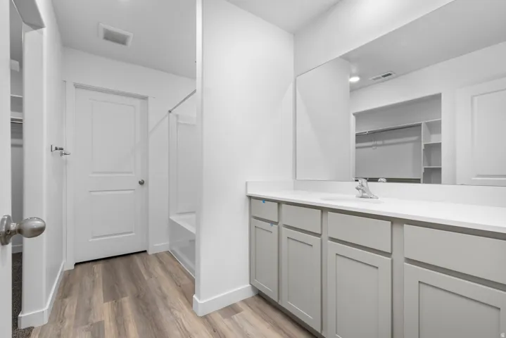 Contemporary bathroom featuring a spacious vanity with light gray cabinetry, white countertop, and a large wall-mounted mirror