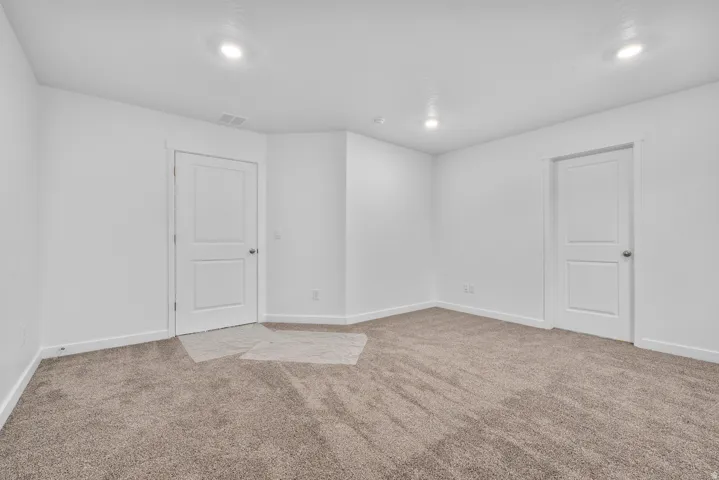 Carpeted room with recessed lighting and white baseboards