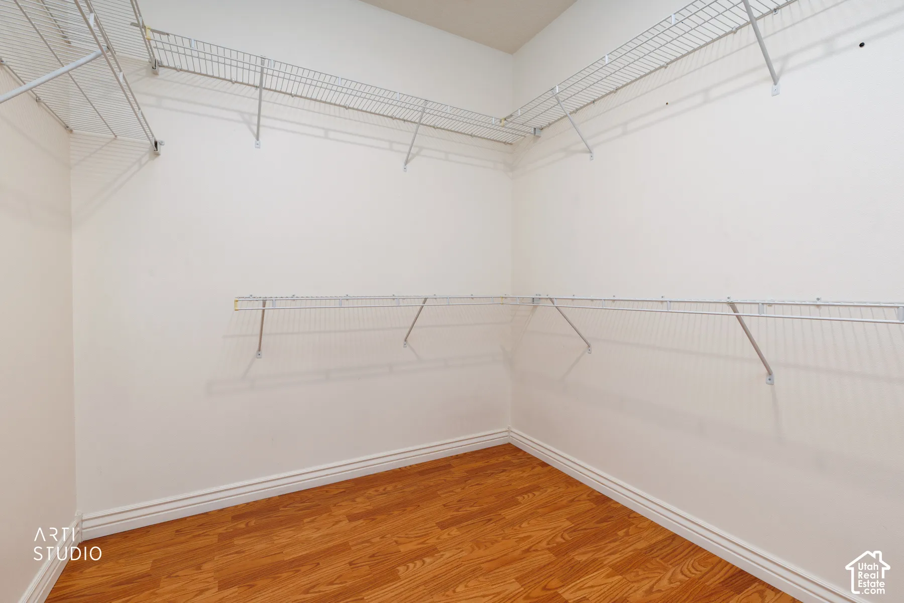 Walk-in closet featuring wood-finish flooring, white baseboards, and comprehensive wire shelving systems