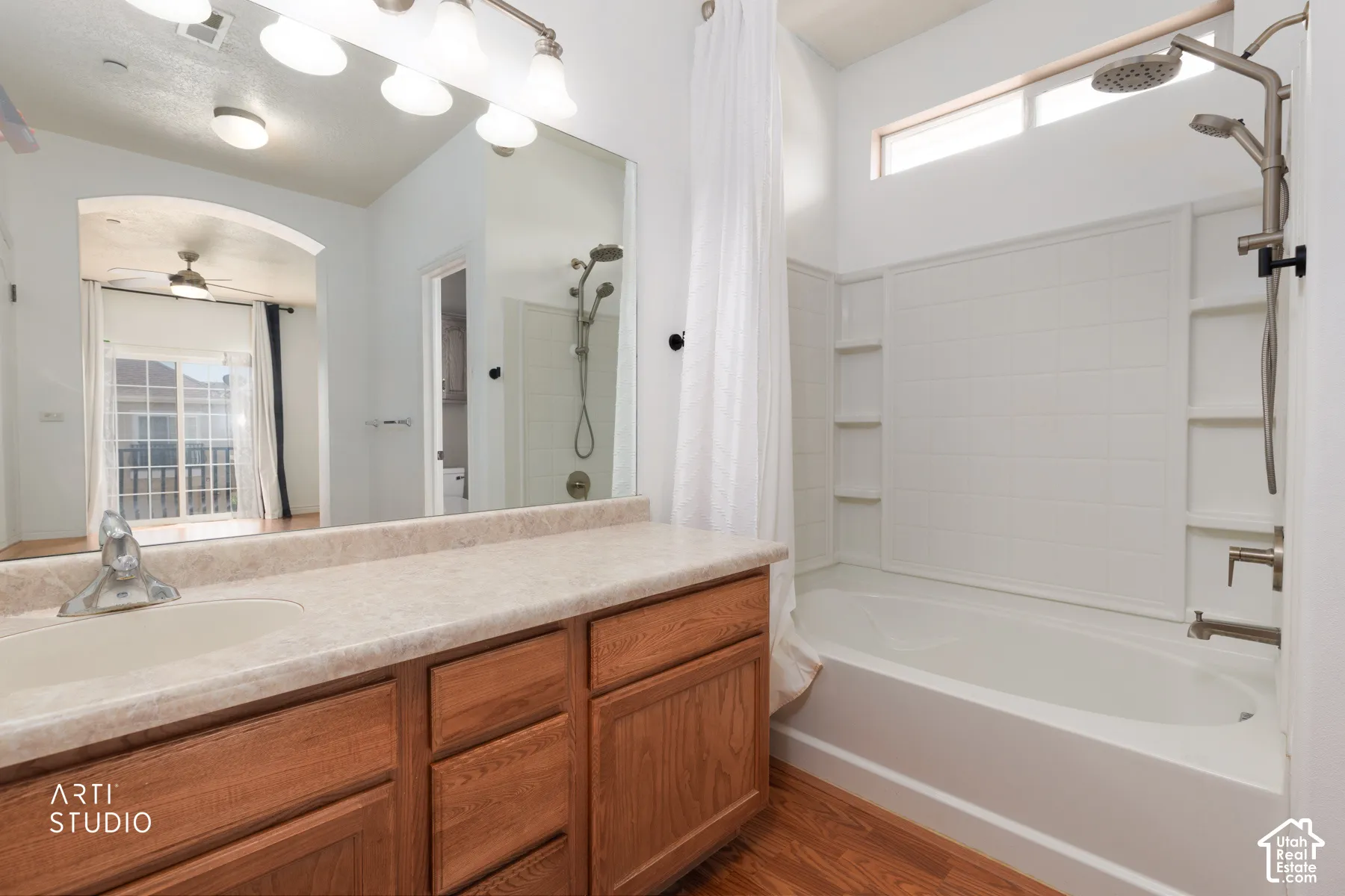 Bathroom featuring a light wood-finish vanity with a single basin sink, spacious countertop, and full-width mirror
