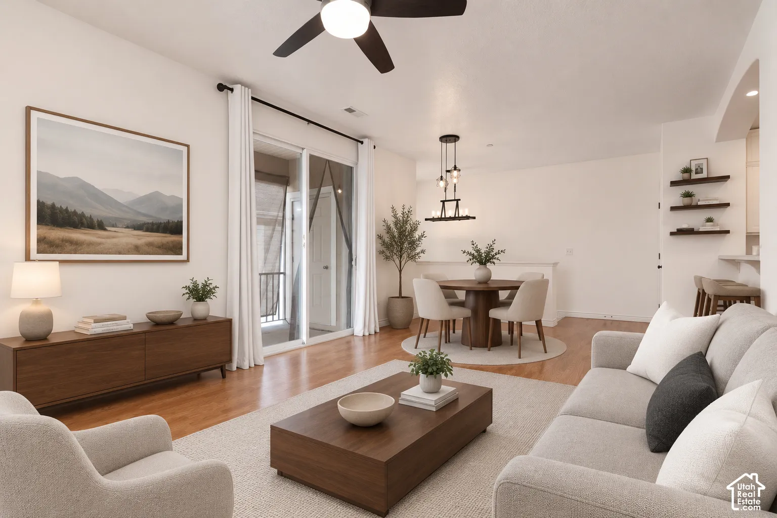 VIRTUALLY STAGED* Open-concept living space with wood-finish flooring, a contemporary ceiling fan, and sliding glass doors to a private balcony