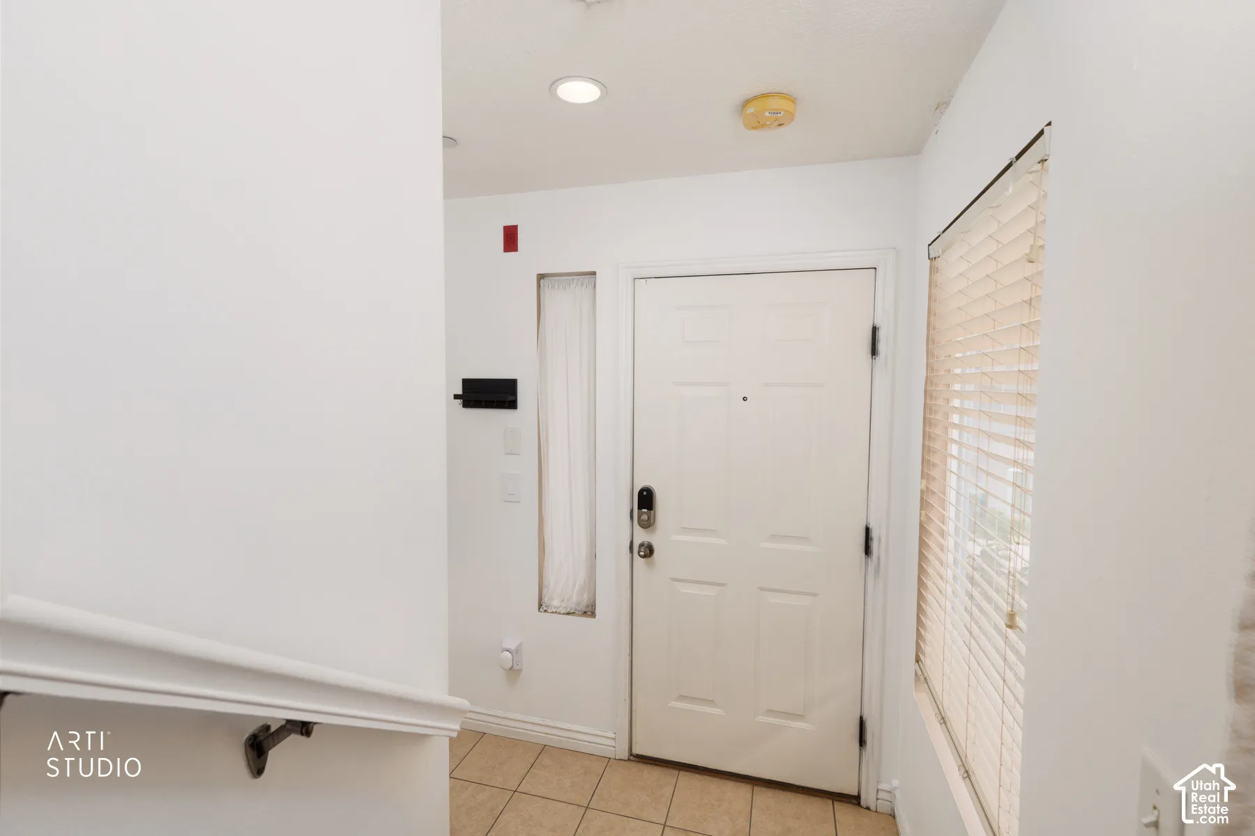 Entryway featuring a paneled door with smart lock, natural light from a window with blinds, recessed lighting, and tile flooring