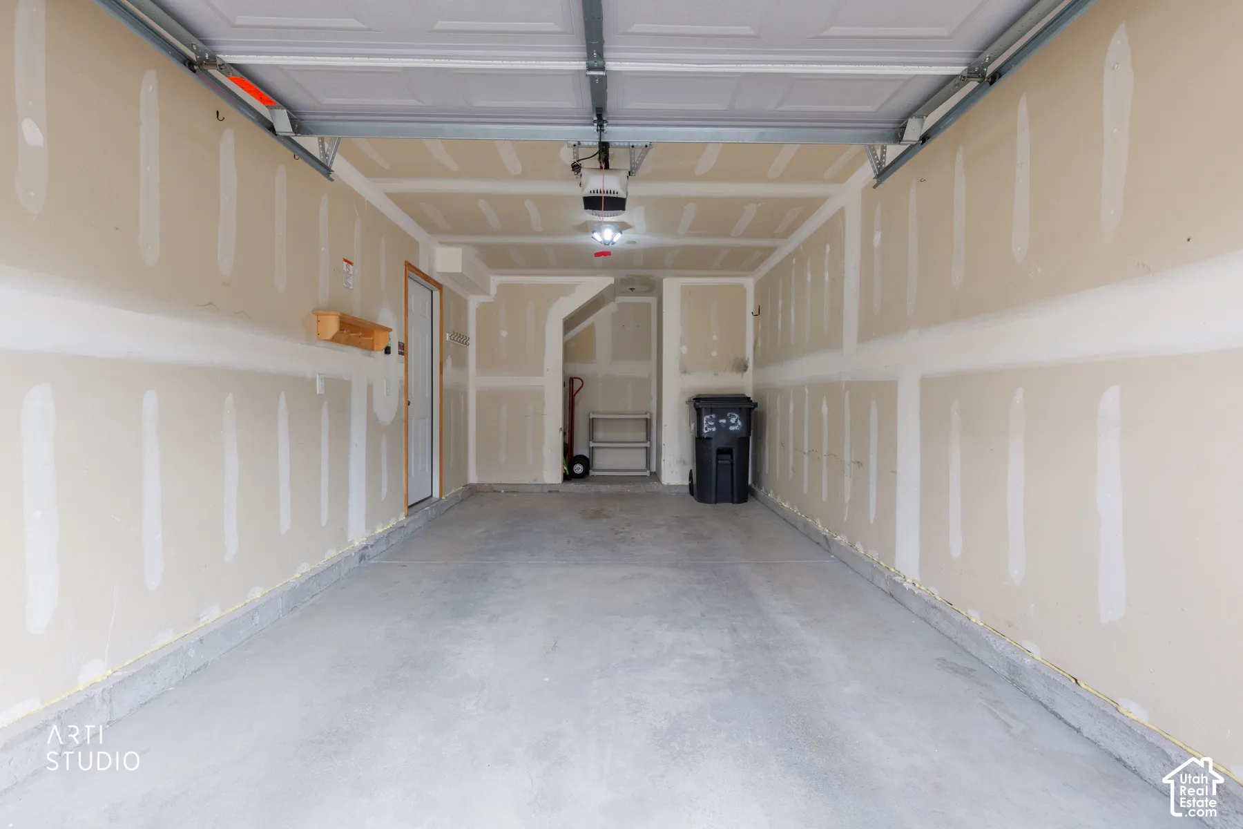 Two-car garage featuring a concrete floor, automatic garage door opener, and interior access door