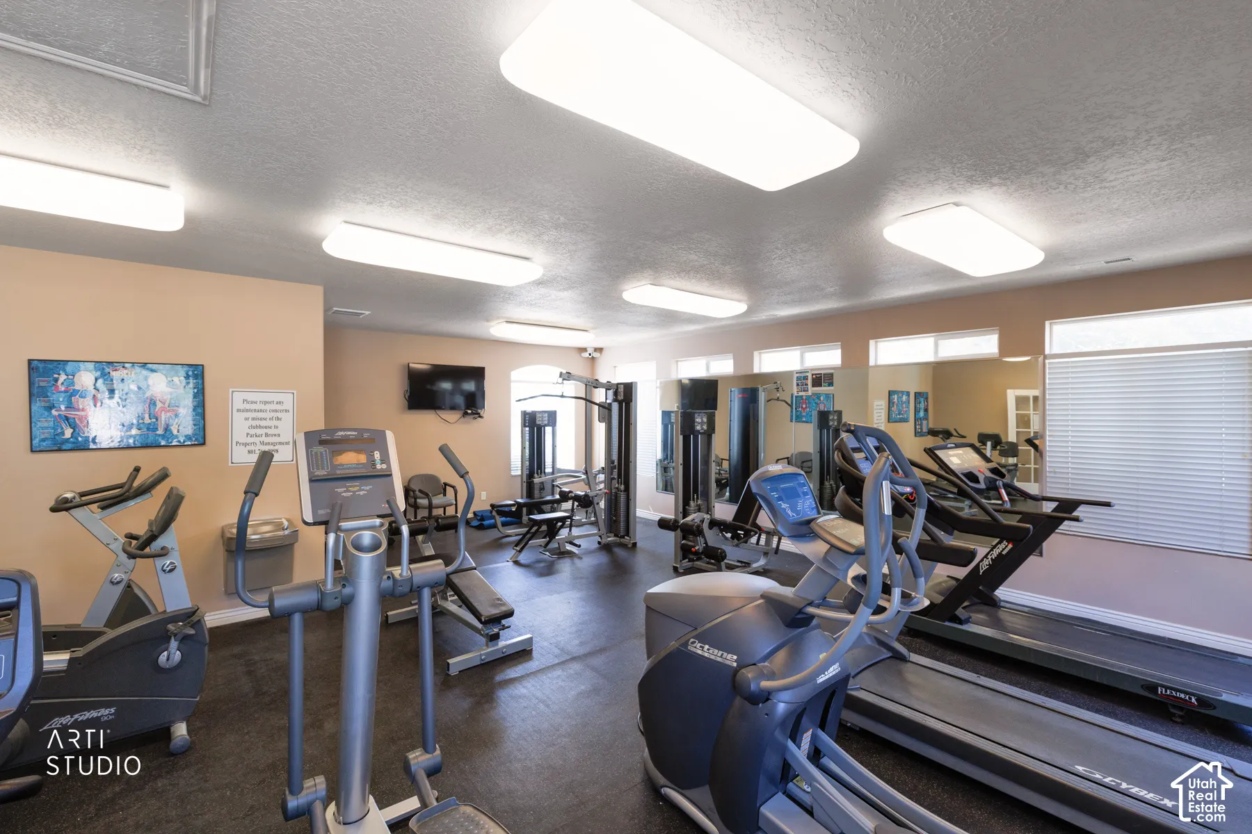 Dedicated fitness center featuring multiple cardio machines, weight training equipment, mirrored walls, and mounted televisions