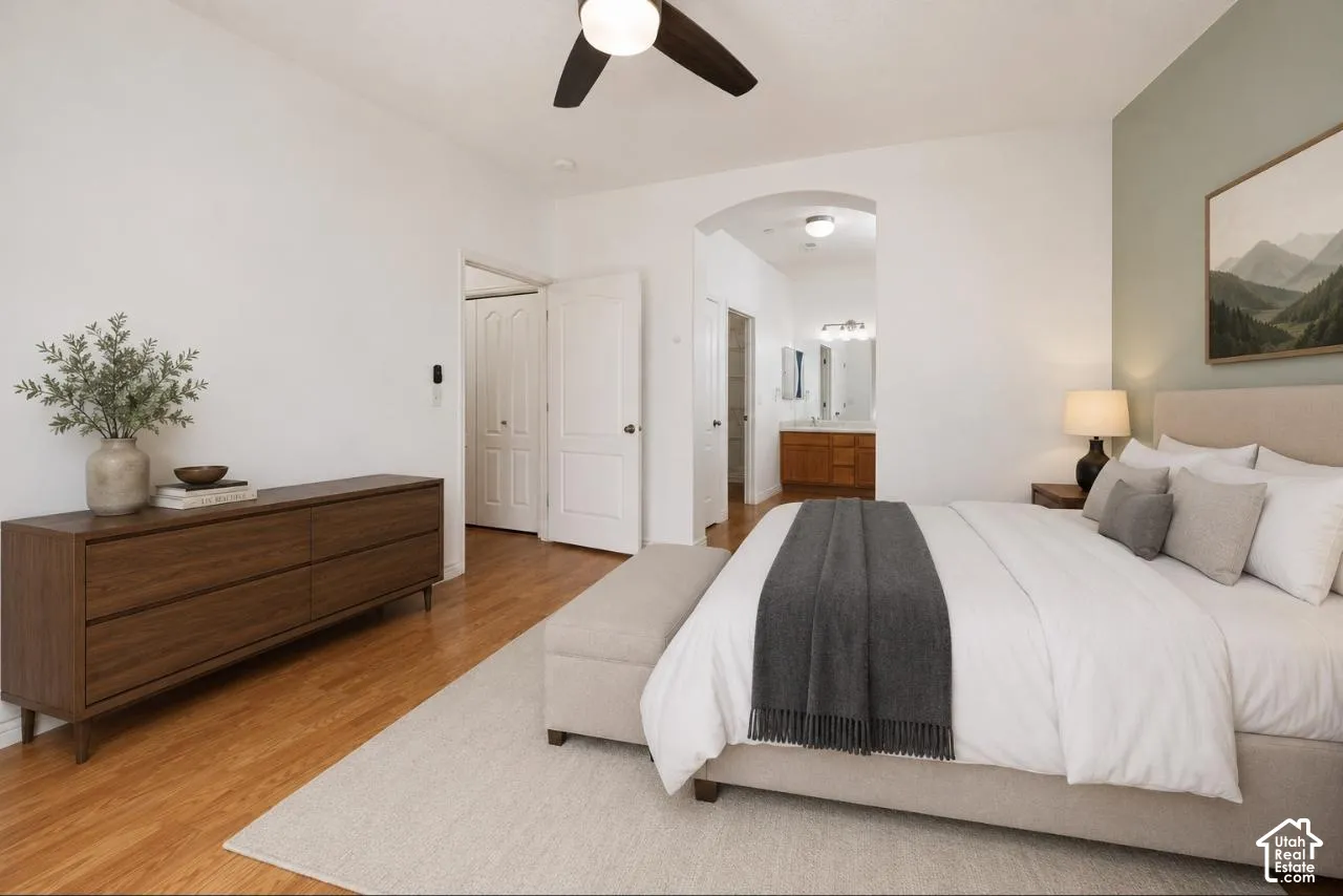 VIRTUALLY STAGED* Spacious bedroom featuring wood-finish flooring, a contemporary ceiling fan, and a light-colored accent wall