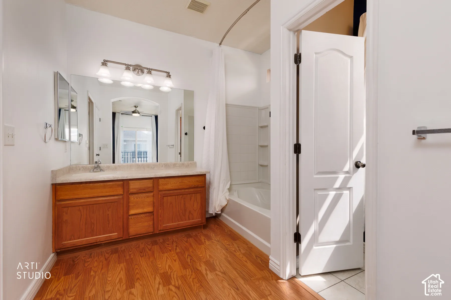Bathroom featuring a wood-finish vanity with a light-colored countertop and an integrated sink