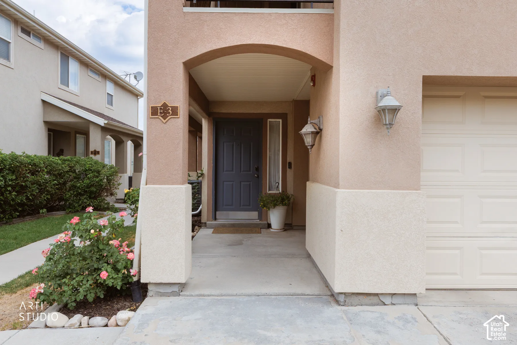 Entryway featuring an arched portico, stucco exterior, panel door, and integrated garage access
