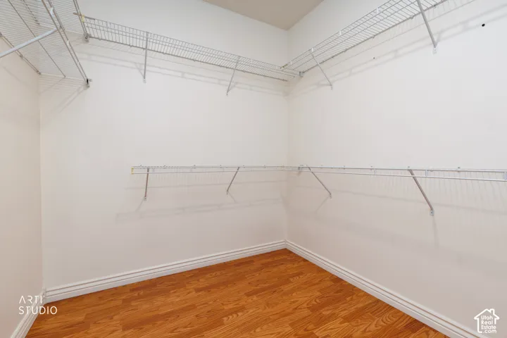 Walk-in closet featuring wood-finish flooring, white baseboards, and comprehensive wire shelving systems