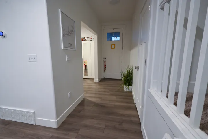 Hallway featuring wood-finish flooring, white trim, and a white interior door with a frosted glass pane